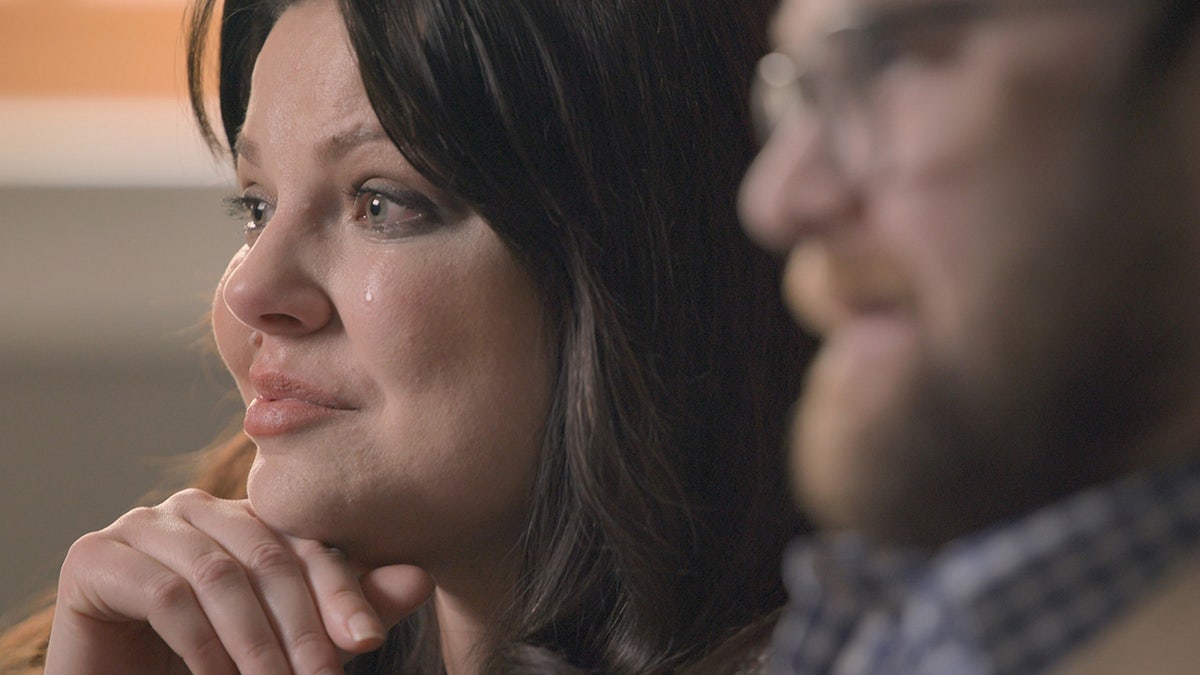 Un primer plano de Amy Duggar King llorando sentada junto a su marido.