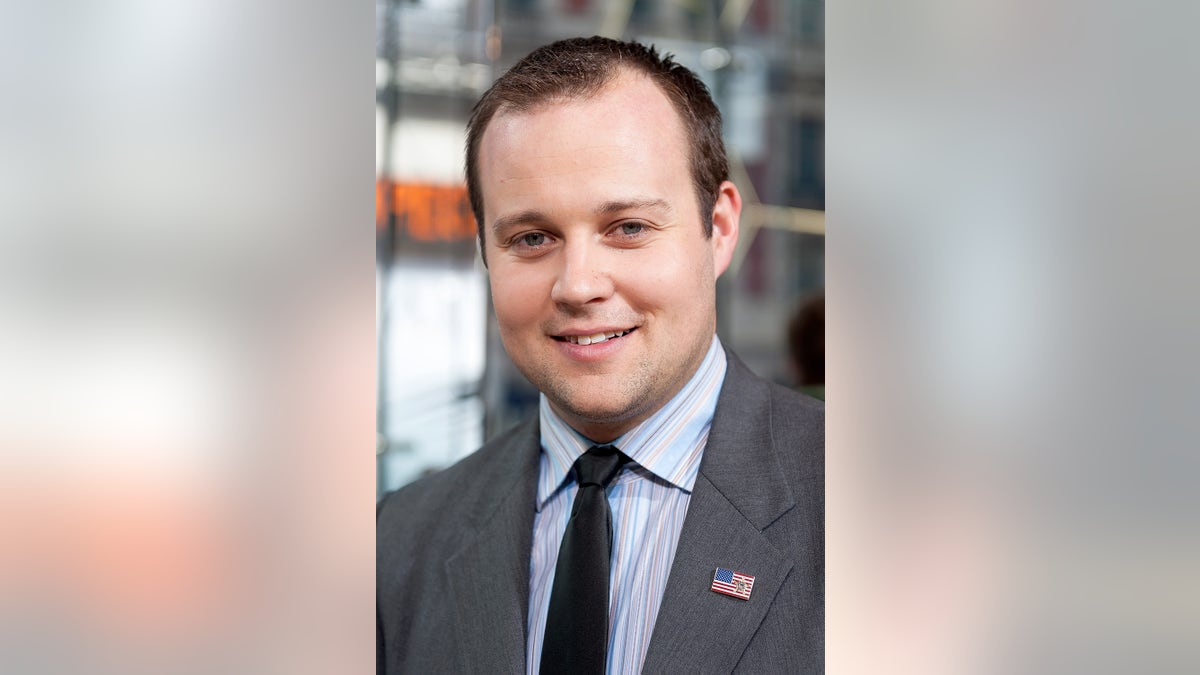 Un primer plano de Josh Duggar sonriendo vestido de traje.