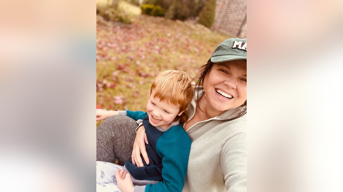 Amy Duggar King tomándose un selfie y sonriendo mientras se hace un selfie con su hijo.