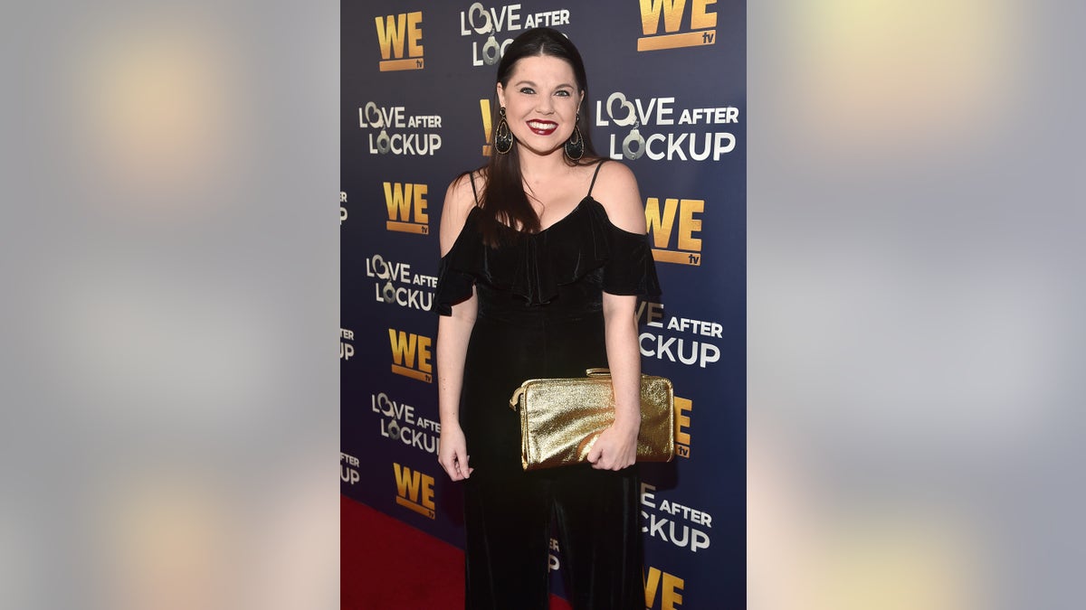 Amy Duggar King luciendo un mono negro off the shoulder en la alfombra roja.