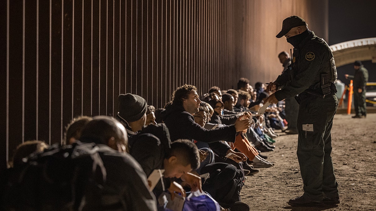 Un agente de CBP y migrantes