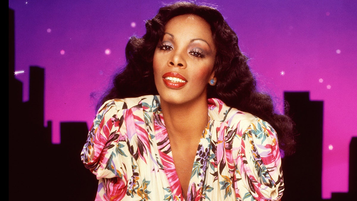 Un primer plano de Donna Summer inclinada con un vestido floral