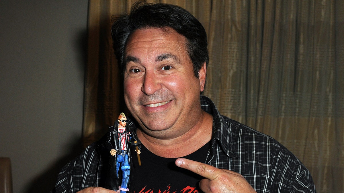 Brian Peck sostiene una muñeca en la convención de cómics