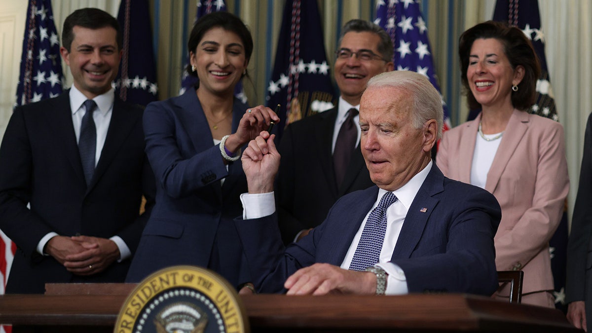 El presidente de la FTC le entrega un bolígrafo a Biden