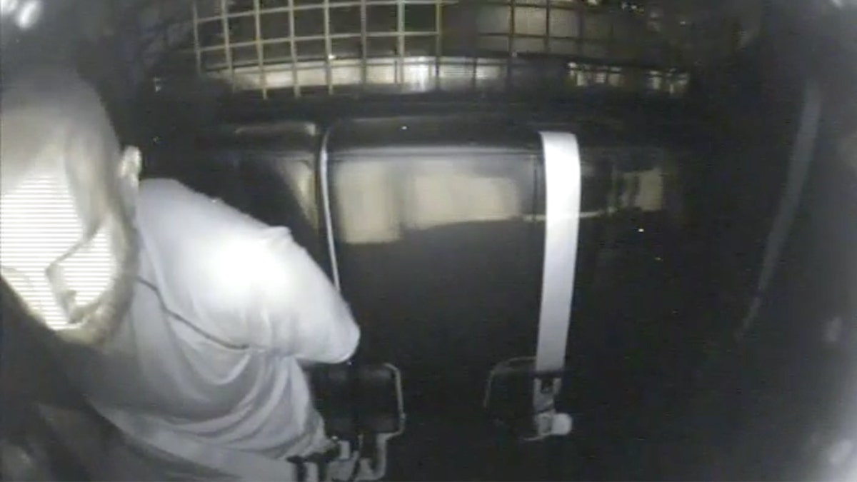 Jeremy Guthrie esposado en la parte trasera del crucero policial