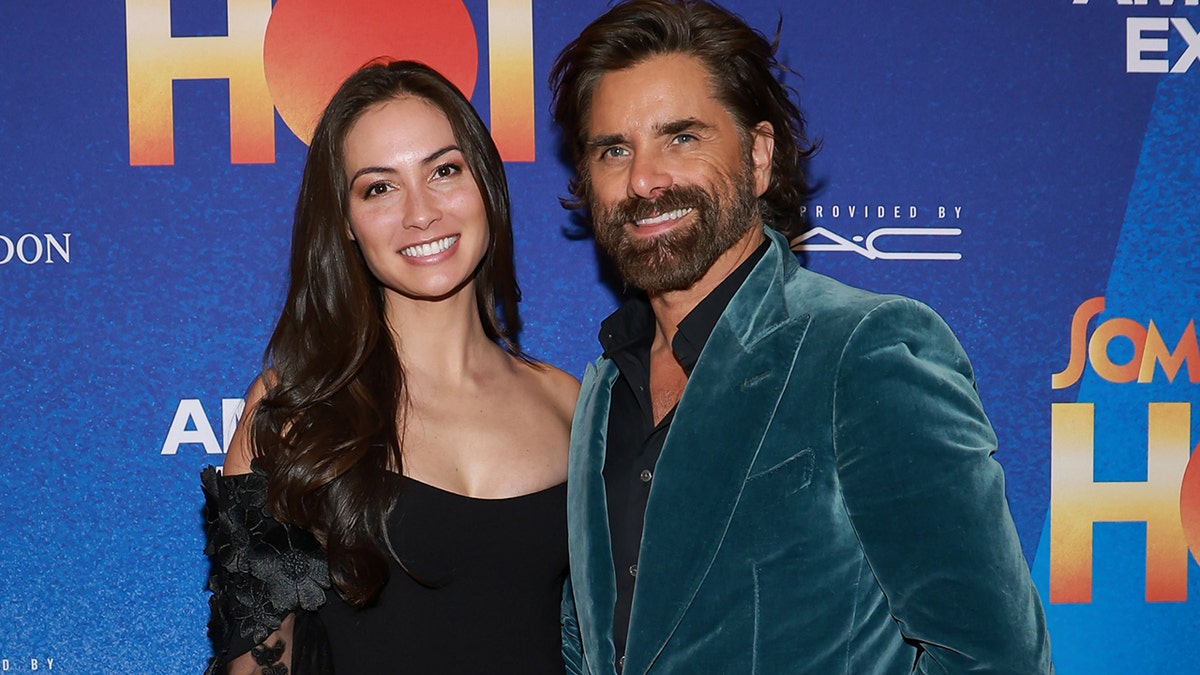 Traje deportivo de terciopelo John Stamos en la alfombra roja con su esposa Caitlin McHugh