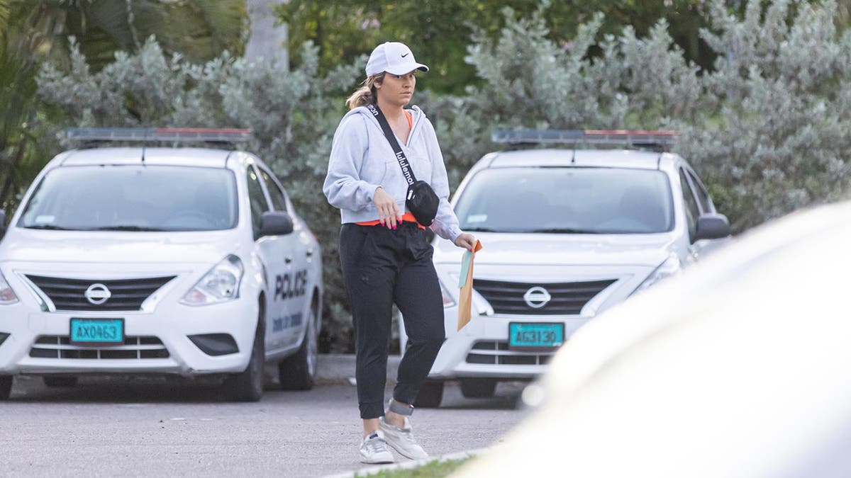 Lindsay Shiver con equipo de entrenamiento camina por un estacionamiento sosteniendo una carpeta manila