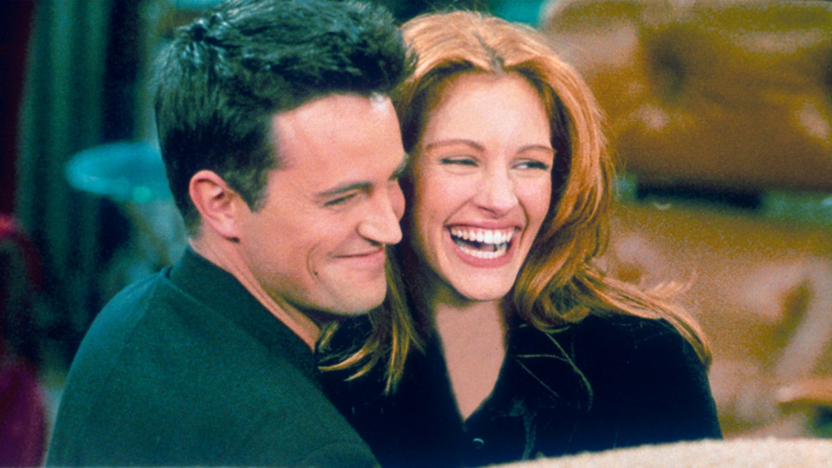Matthew Perry como Chandler en el set de "Friends" abraza a la actriz Julia Roberts