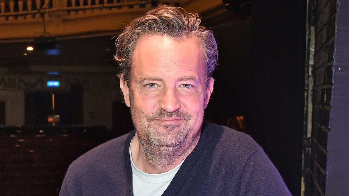 Matthew Perry usa suéter y camiseta azules en el evento