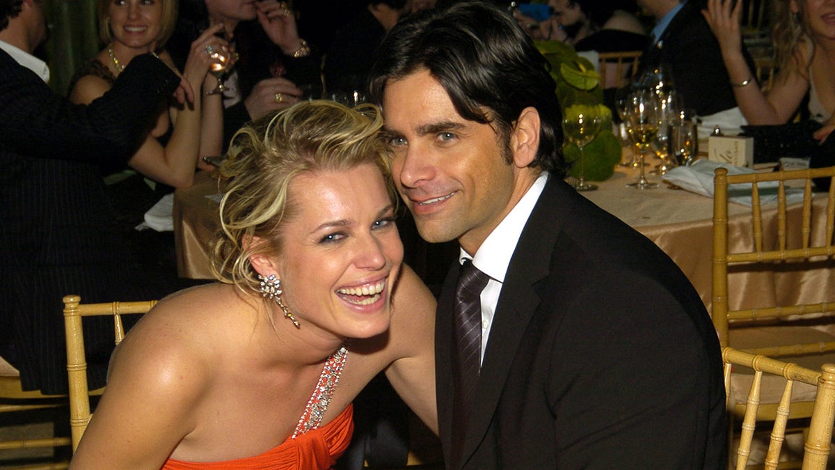 Rebecca y John sentados juntos y sonriendo