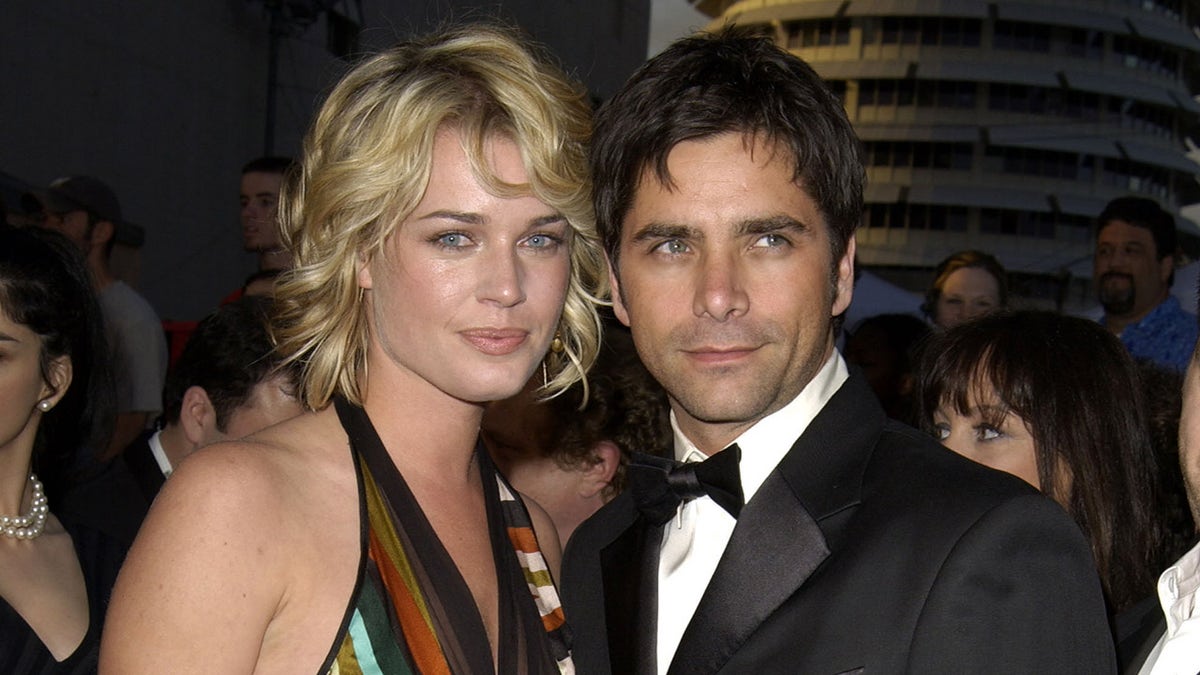 Rebecca Romijn camina por la alfombra roja con John Stamos con un esmoquin