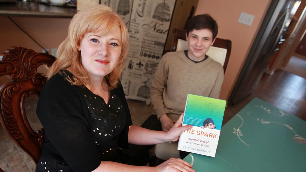 Kristine Barnett sosteniendo un libro junto a su hijo