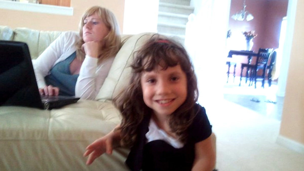 Natalia Grace sonriendo mientras Kristine Barnett mira hacia otro lado a una computadora