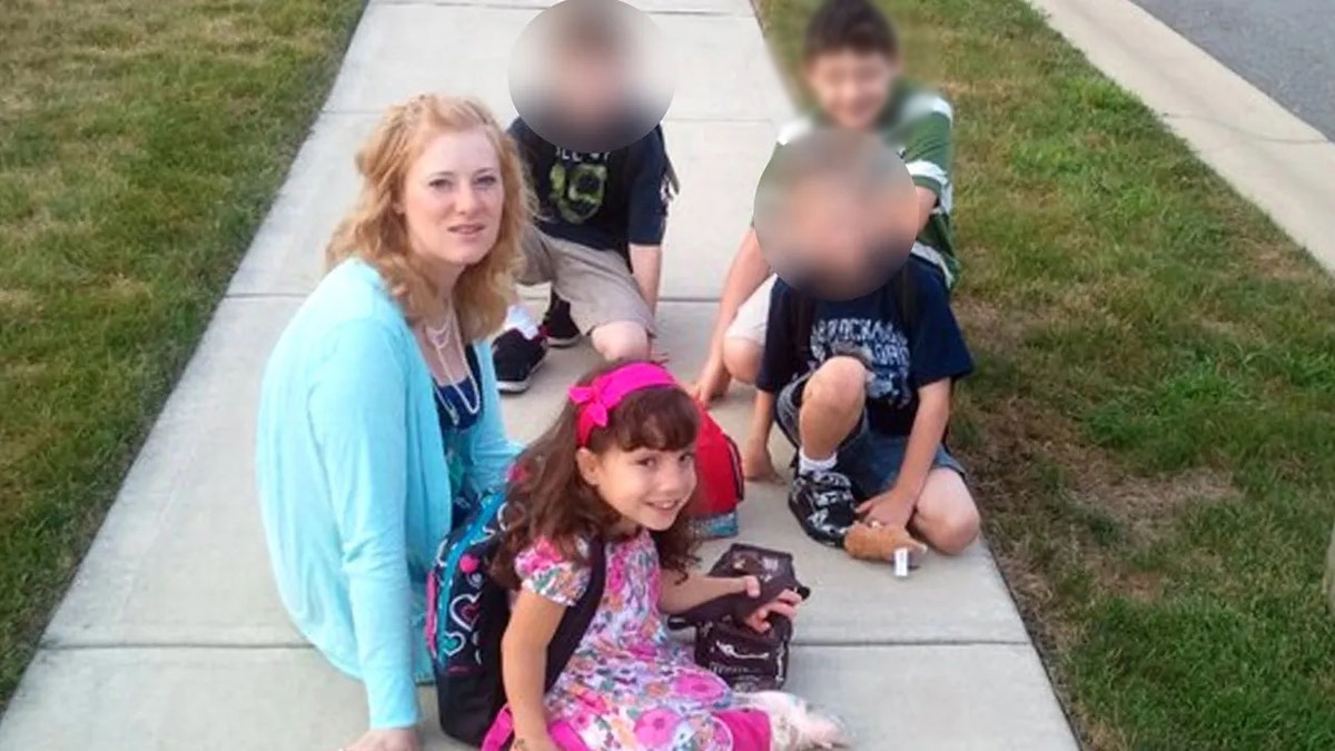 Kristine Barnett con un suéter azul brillante sentada en la acera con sus hijos