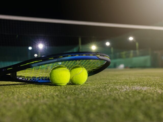 juegue al tenis en la oscuridad con iluminación artificial. raqueta y pelotas en cancha al aire libre con copia